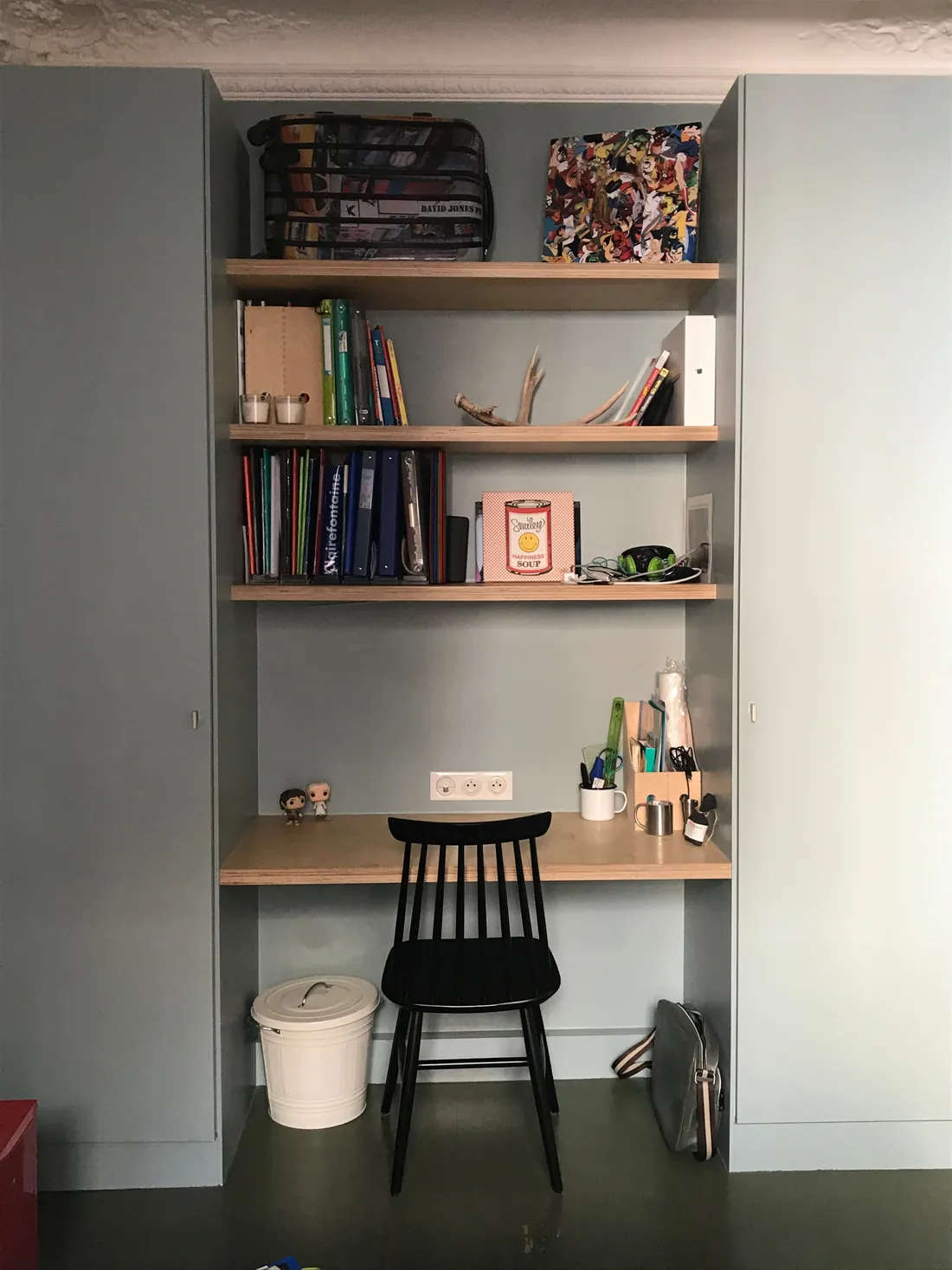 Bureau d'enfant sur mesure logé entre deux armoires toute hauteur gris bleu, plateau et étagères en chêne clair, chaise noire à barreaux