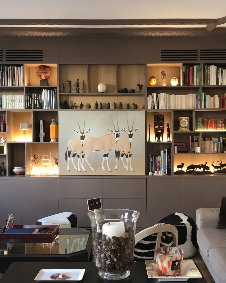 Bibliothèque sur mesure aux caissons gris et fond de chêne, intégrée sous un plafond à poutres moulurées, avec grilles de ventilation du home cinéma