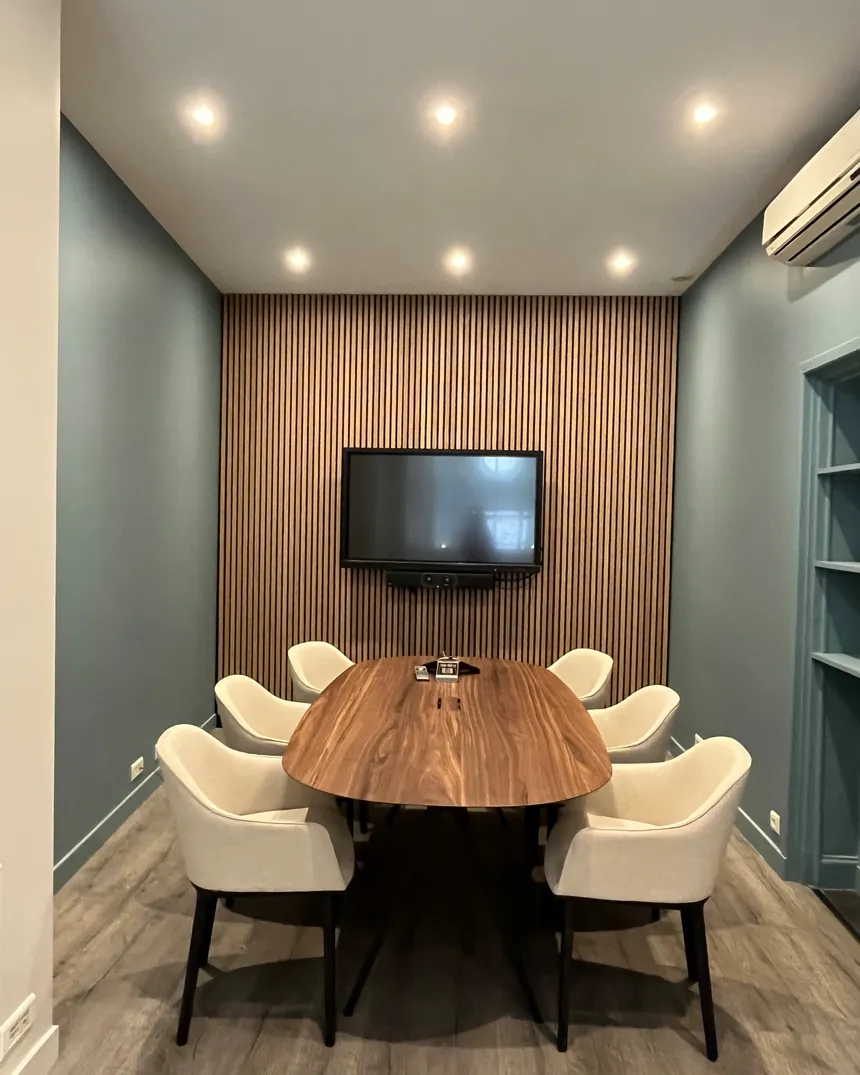 Salle de réunion aménagée dans un hôtel particulier parisien : grande table en noyer, mur en tasseaux de bois et peinture vert d'eau
