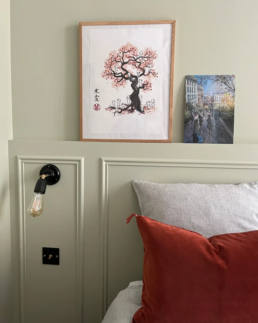 Bibliothèque et rangements sur mesure peints en vert d'eau dans une chambre, étagères garnies de livres, portes à moulures et boutons noirs