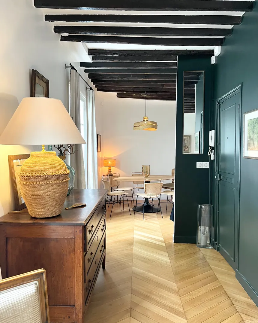 Enfilade d'un duplex ancien à Paris 17e : poutres apparentes, parquet point de Hongrie et porte vert sapin
