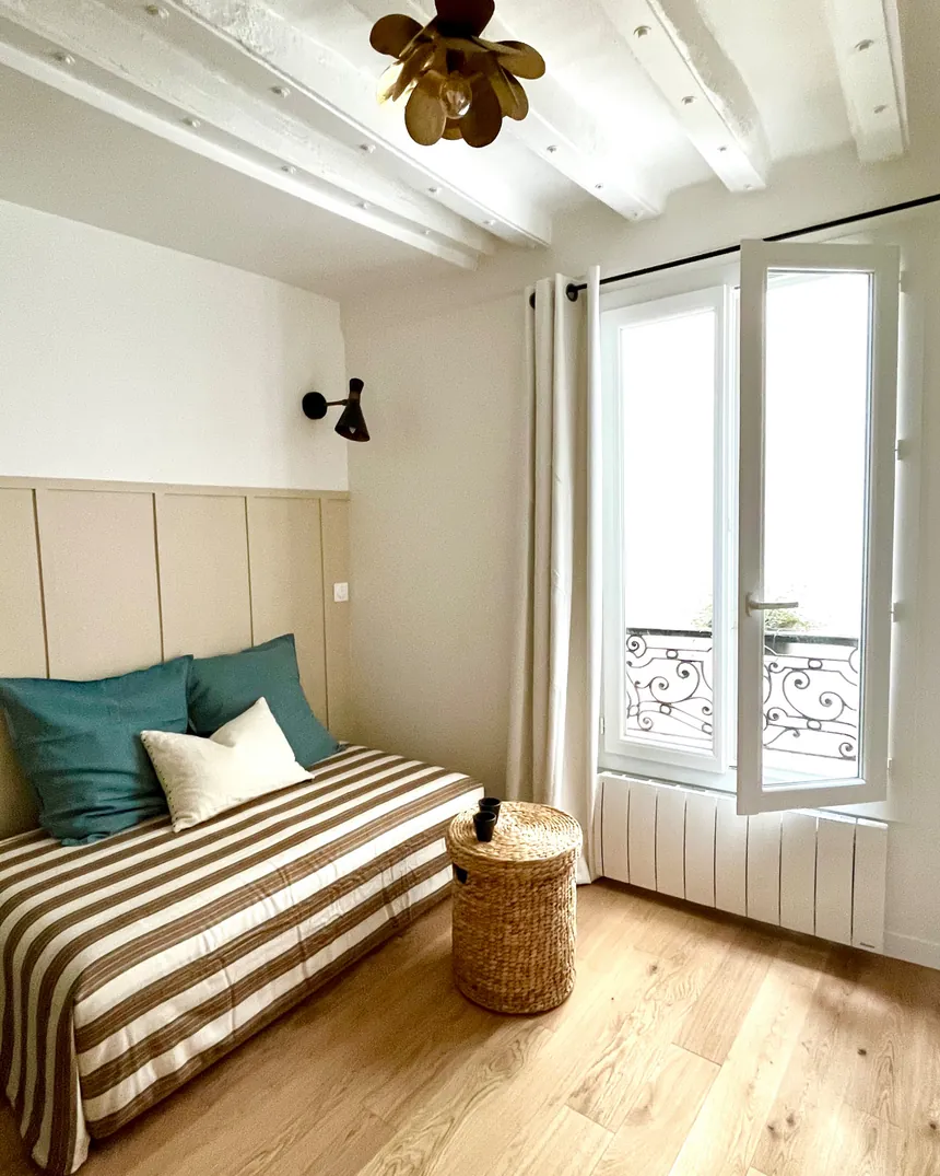 Studio de 13 m² rénové à Paris 3e : lit en alcôve, tête de lit bleu canard et fenêtre donnant sur la rue